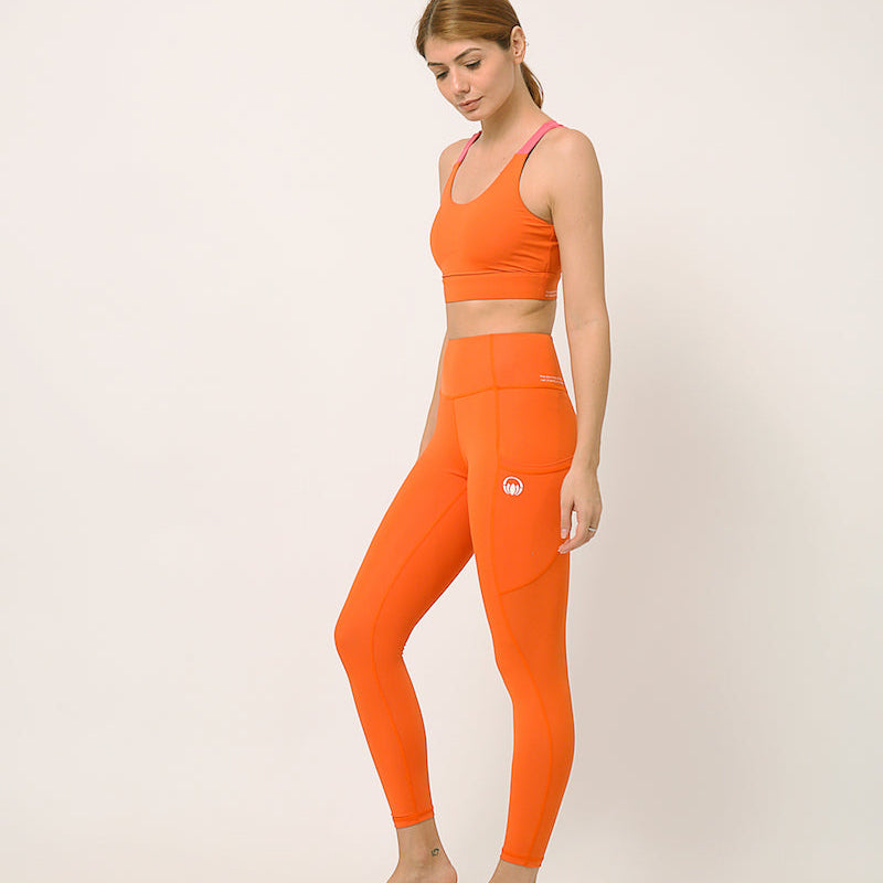 Orange yoga pants and sports bra for yoga, gym, workouts, running made by kosha yoga co from recycled materials