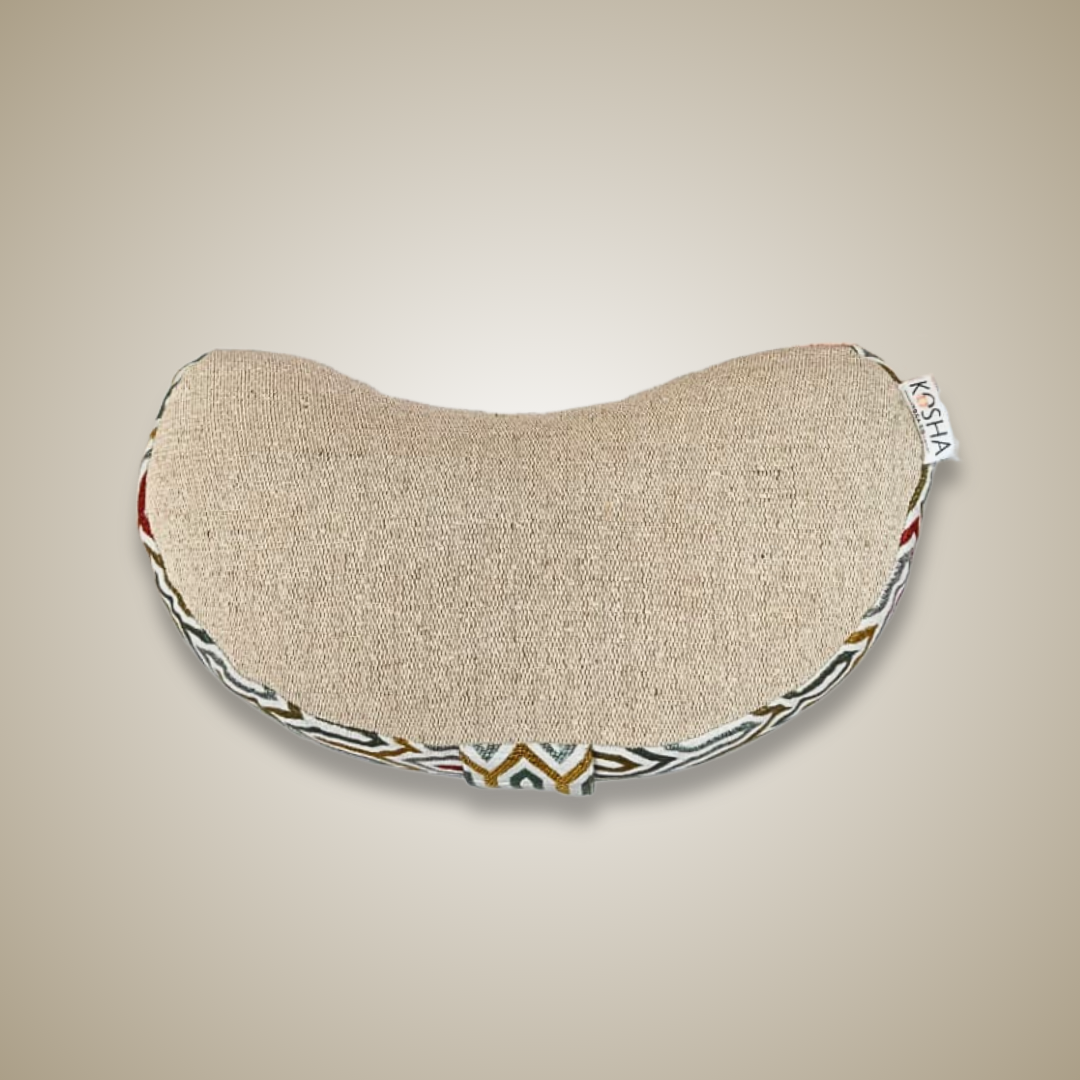 Half-moon shaped pillow with decorative edge on a beige background