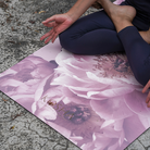 Person sitting on a floral-patterned yoga mat outdoors pink yoga mat kosha yoga