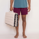 Man carrying a folded ivory and black Kosha meditation cushion by its handle