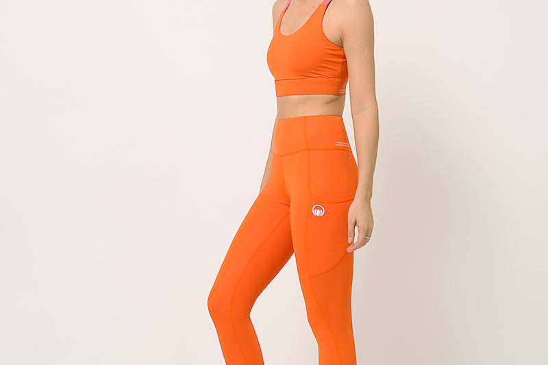 Orange yoga pants and sports bra for yoga, gym, workouts, running made by kosha yoga co from recycled materials