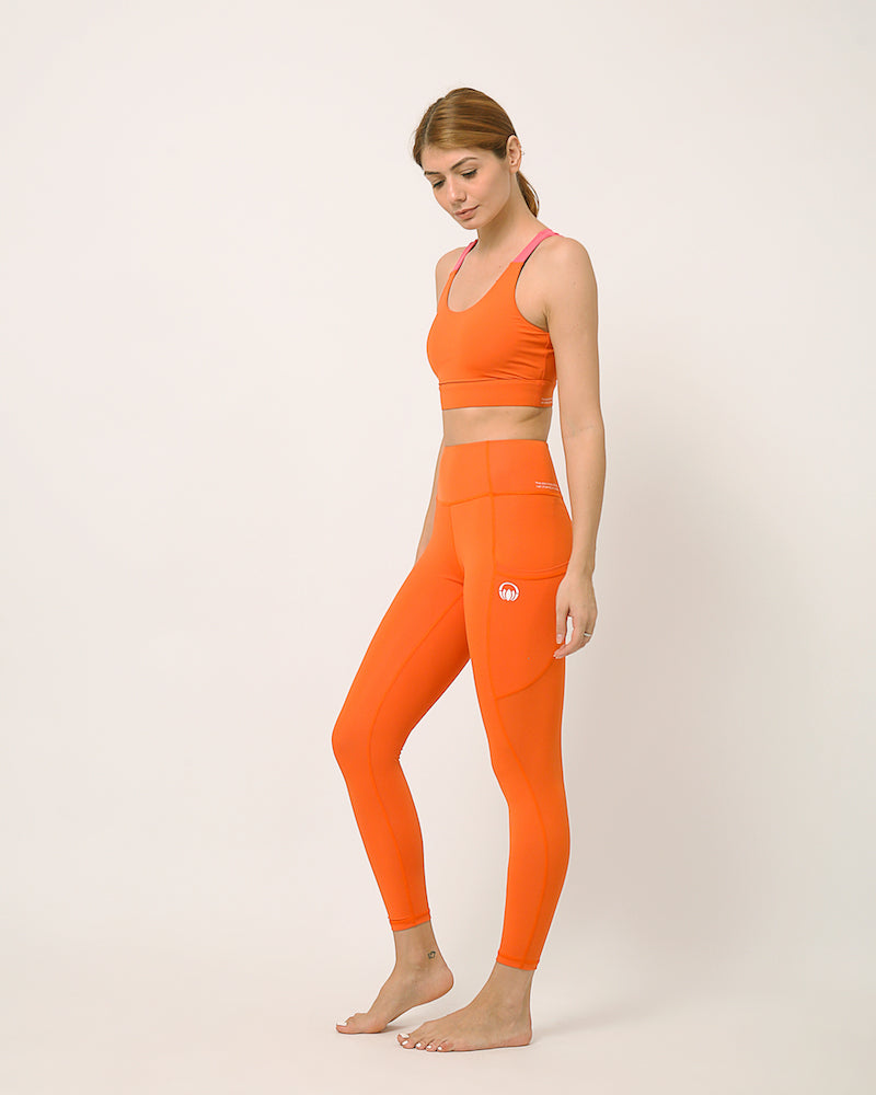 Orange yoga pants and sports bra for yoga, gym, workouts, running made by kosha yoga co from recycled materials
